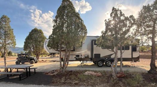An rv site with a fifth wheel camper and a side by side at Soda Creek Campground in Soda Springs, Idaho.